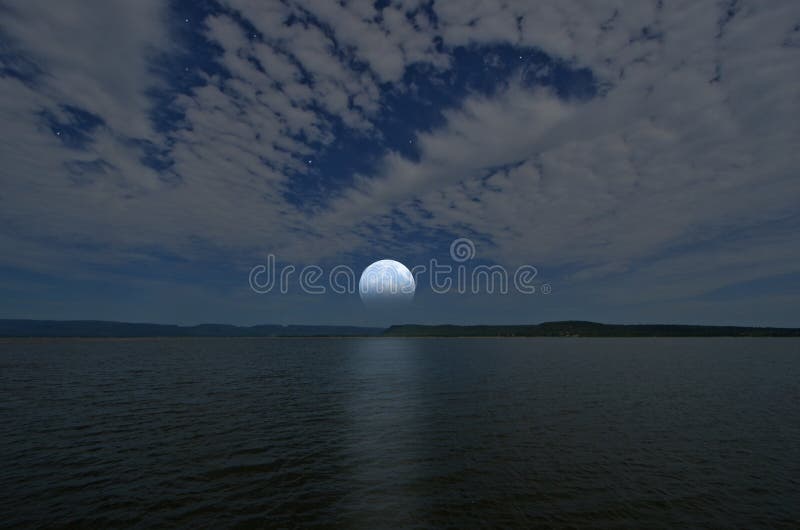 Luna Llena y nubes blancas hermosas en cielo azul sobre el lago y las montañas foto de archivo libre de regalías Luna Llena y nubes blancas hermosas en cielo azul sobre el lago y las montañas foto de archivo libre de regalías