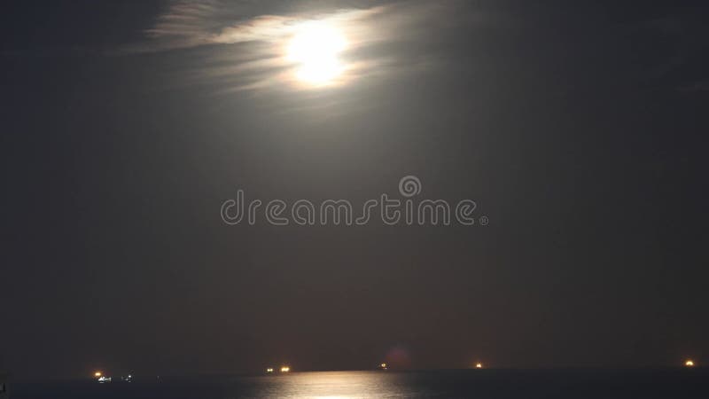 Luna piena sorge gettando nuvole di mare nelle notti abbracciando. La scena mostra una nuvola di luna sul mare delle coste. navi