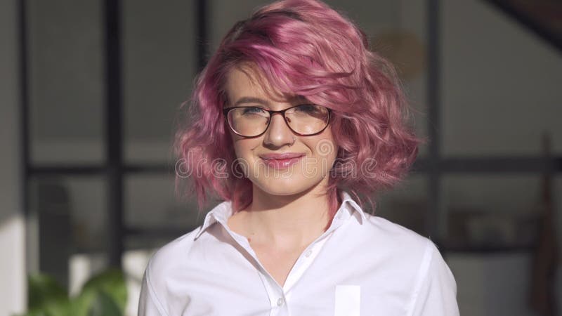 Lunettes de l'adolescence de sourire d'usure de poils de rose de la fille de jeune hippie est confrontée l'intérieur le portrait. banque de vidéos