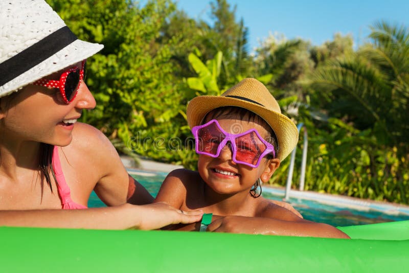 Lunettes de soleil de port heureuses de mère et de garçon dans la piscine photo stock Lunettes de soleil de port heureuses de mère et de garçon dans la piscine photo stock
