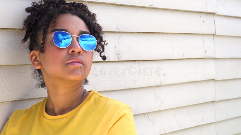 Lunettes de soleil de port de métis afro-américaine de jeune femme adolescente de fille reflétant le ciel bleu et les nuages banque de vidéos