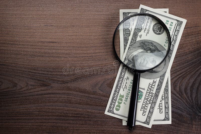 Magnifying glass and money on the wooden background. Magnifying glass and money on the wooden background