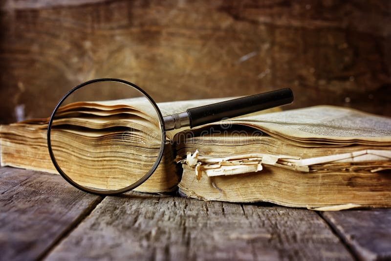 Magnifying glass and old book on wooden table. Magnifying glass and old book on wooden table