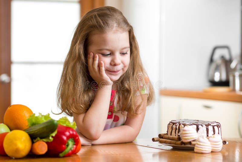 Kid girl choosing between healthy vegetables and tasty sweets. Kid girl choosing between healthy vegetables and tasty sweets