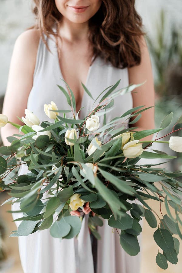 A Lush Bouquet of Eucalyptus and Tulips in the Hands of a Woman Stock