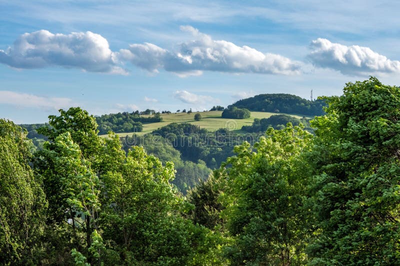 Svěží zeleň na pozadí modré oblohy s nadýchanými mraky. Banská Bystrica, Slovensko.