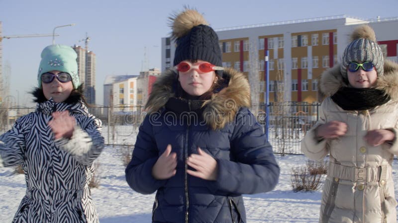 Lustig Jugendlichmädchen dem Schutzbrillenschwimmen im Freien Winterstadtlandschaft. greller Mob der spielerischen Mädchenjugendli