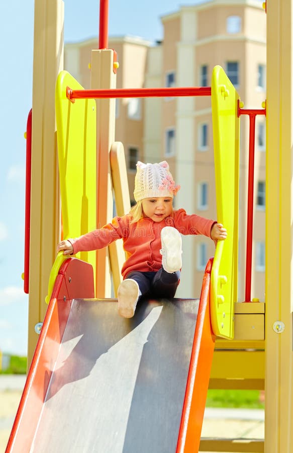 Lustig wenig Mädchen auf Spielplatz Kind auf Dia lizenzfreies stockbild Lustig wenig Mädchen auf Spielplatz Kind auf Dia lizenzfreies stockbild