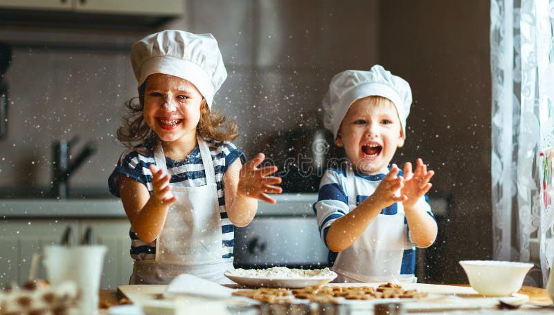 Lustige Kinder der glücklichen Familie backen Plätzchen in der Küche