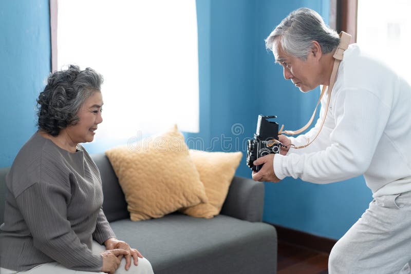 Lustige Zeit! Reifer Mannphotograph, der den Spaß spielt hat, Foto von künstlerischem seine Frau zu Hause machend Foto für Gedäch lizenzfreies stockfoto Lustige Zeit! Reifer Mannphotograph, der den Spaß spielt hat, Foto von künstlerischem seine Frau zu Hause machend Foto für Gedäch lizenzfreies stockfoto
