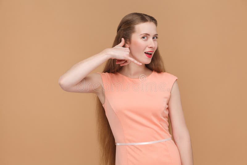 Funny girl shows call sing, looking at camera and asking. portrait of emotional cute, beautiful woman with makeup and long hair in pink dress, studio shot isolated on light brown or beige background. Funny girl shows call sing, looking at camera and asking. portrait of emotional cute, beautiful woman with makeup and long hair in pink dress, studio shot isolated on light brown or beige background.