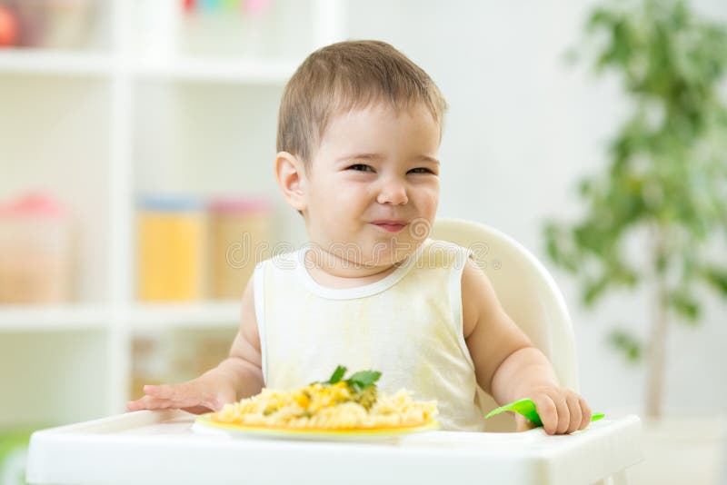 Lustiges Baby, das gesundes Lebensmittel im Kindertagesstätte isst stockfotografie Lustiges Baby, das gesundes Lebensmittel im Kindertagesstätte isst stockfotografie