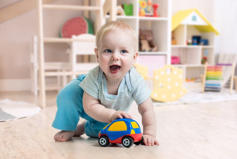 Lustiges Baby, das Spielzeug in der Kindertagesstätte spielt lizenzfreie stockfotos Lustiges Baby, das Spielzeug in der Kindertagesstätte spielt lizenzfreie stockfotos