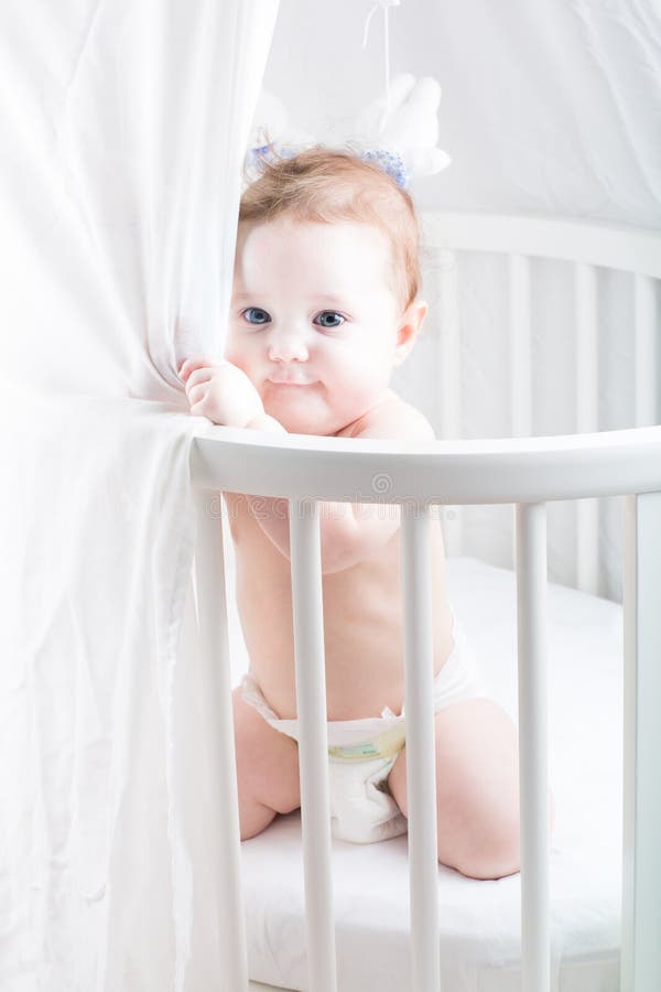 Lustiges Baby in einer Windel, die in seiner Krippe spielt lizenzfreie stockfotografie Lustiges Baby in einer Windel, die in seiner Krippe spielt lizenzfreie stockfotografie