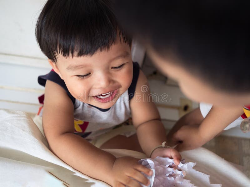 Lustiges Baby genießen, ein Stückpapier zusammen zu spielen stockfotografie Lustiges Baby genießen, ein Stückpapier zusammen zu spielen stockfotografie