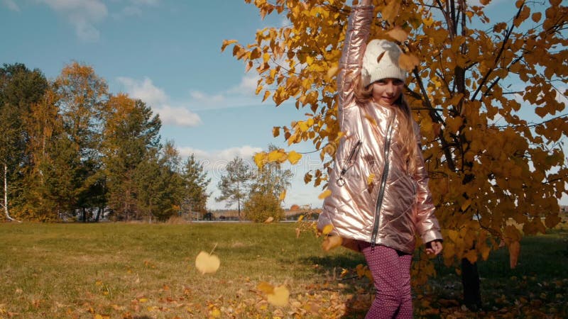 Lustiges Jugendlichmädchen, das Herbstlaub in den Händen hält und in Herbstlaub tanzt