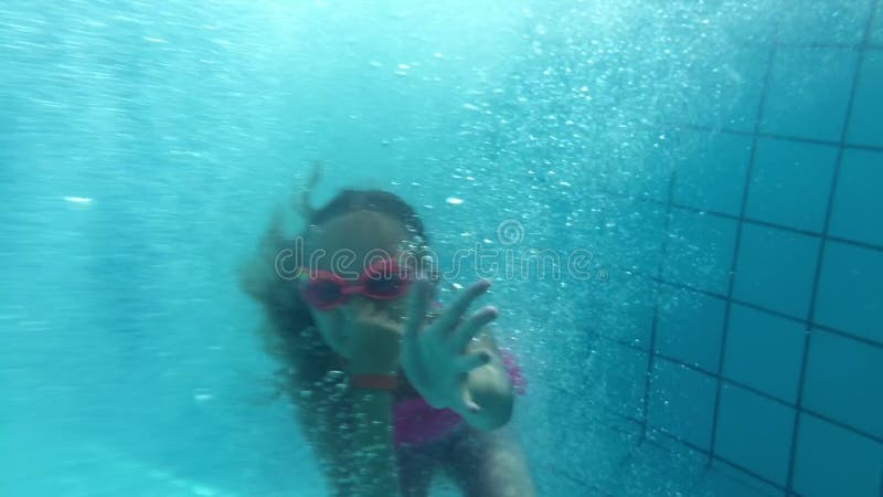 Lustiges Jugendlichmädchentauchen in Wasser im Swimmingpool im Sommerhotel