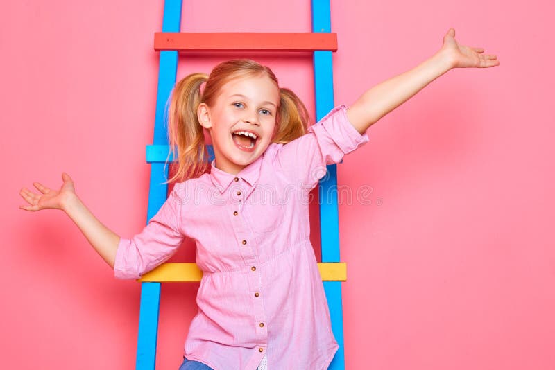 Lustiges kleines Mädchen, das auf der Treppe, den wellenartig bewegenden Händen und dem Lachen sitzt stockbild Lustiges kleines Mädchen, das auf der Treppe, den wellenartig bewegenden Händen und dem Lachen sitzt stockbild