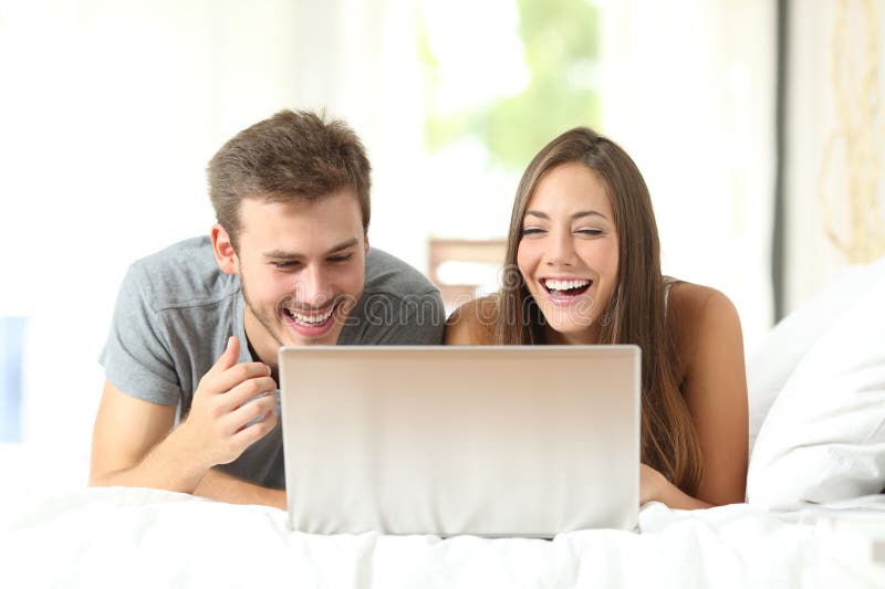 Lustiges Paar lacht, sich die Inhalte von Laptops anzusehen