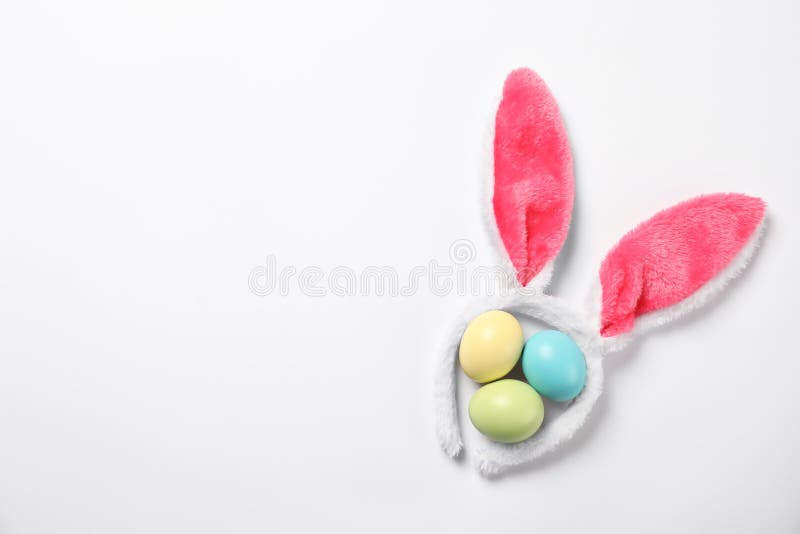 Lustiges Stirnband mit den Osterhasenohren und gefärbtem weißem Hintergrund der Eier stockfotos
