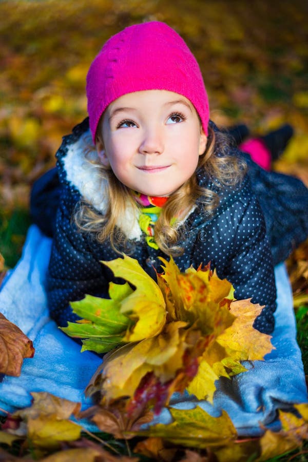 Lustiges träumendes schönes kleines Mädchen, das mit Ahornblättern liegt stockfoto Lustiges träumendes schönes kleines Mädchen, das mit Ahornblättern liegt stockfoto