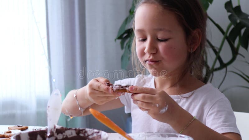 Lustigt glad tjej dansar medan de dekorerar hemmade gingerbröd med isbildning