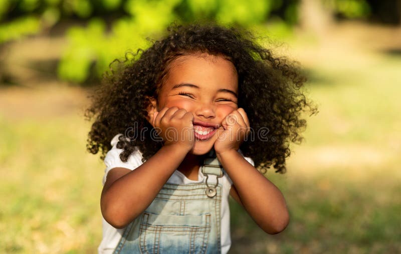 Lustigt lite afro-flicka som rör kinder och har kul arkivbilder