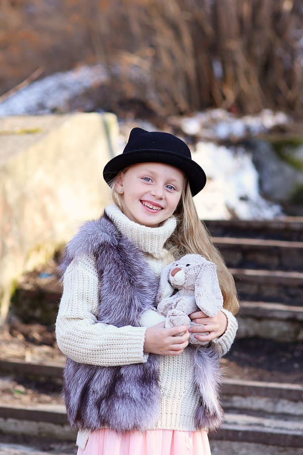 Lustigt sött liten flicka leker och kramar med en kanin leksak utomhus. royaltyfria foton