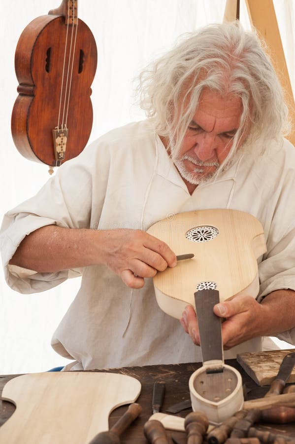 The luthier builds a medieval stringed instrument. Luthier working on the creation of a stringed instrument. Various tools and instrument are placed on the workbench