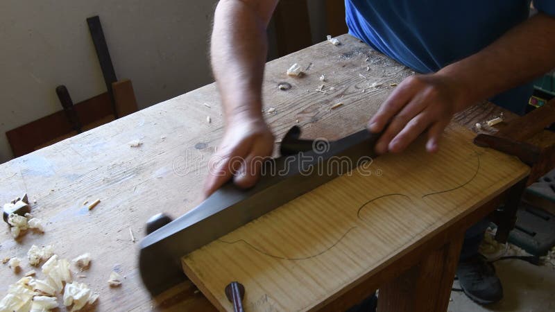 Luthier working in a new violin or viola with a wood planer