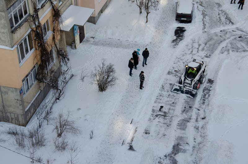 Lutsk, Ukraine - December 2, 2020. Bobcat skid steer loader removes snow from the city streets. Top view of the road with cars and snow blower. Seasonal work in winter snowy city. Lutsk, Ukraine - December 2, 2020. Bobcat skid steer loader removes snow from the city streets. Top view of the road with cars and snow blower. Seasonal work in winter snowy city