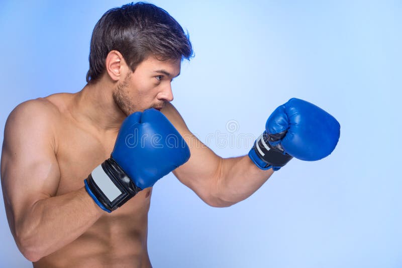 Luvas de encaixotamento vestindo musculares consideráveis do homem novo fotografia de stock royalty free Luvas de encaixotamento vestindo musculares consideráveis do homem novo fotografia de stock royalty free