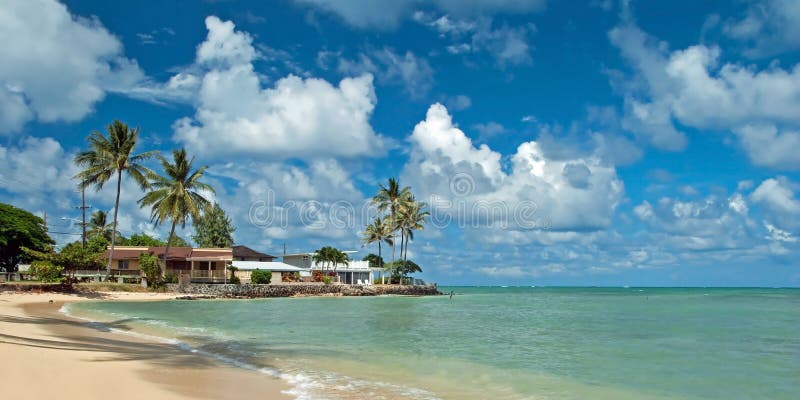 Luxehuis op onaangeroerd zandig strand met palmenbomen en azuurblauw