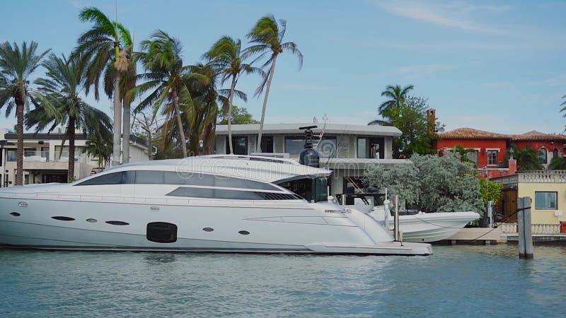 Luxueuze privé boot die dichtbij huis van rijke mensen op stereiland fascineren, zonnig eilandenstrand, Miami