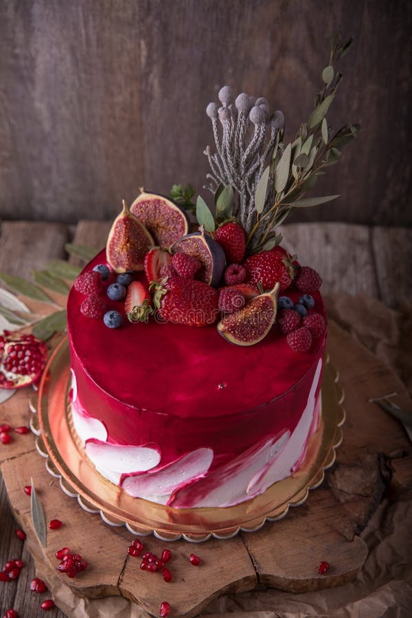 Luxurious wedding or St. Valentine`s cake of burgundy and red shades decorated with juicy strawberries