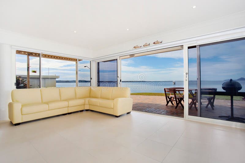 Settee in spacious apartment living room with open sliding doors showing view of waterfront. Settee in spacious apartment living room with open sliding doors showing view of waterfront.