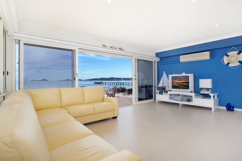 Luxurious, spacious apartment living room with waterfront visible through sliding doors. Luxurious, spacious apartment living room with waterfront visible through sliding doors.