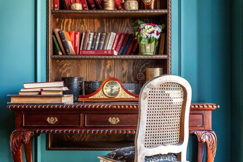 Luxury classic interior of home library. Sitting room with bookshelf, books, table and chair