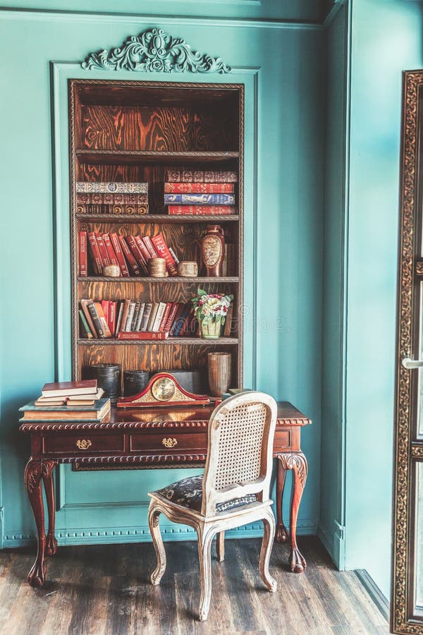 Luxury classic interior of home library. Sitting room with bookshelf, books, table and chair