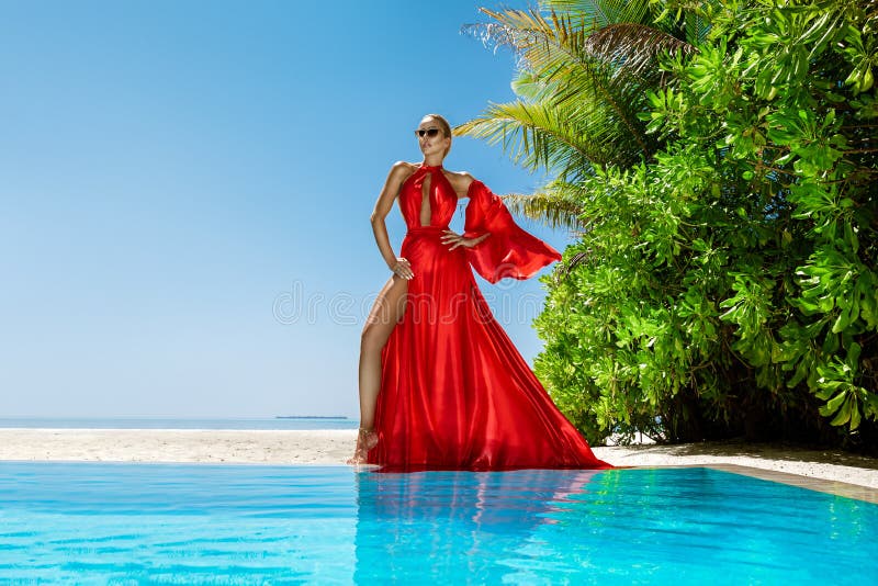 Luxury fashion. Elegant fashion model. Stylish female model in red long gown dress on the Maldives beach. Elegance. Classy woman