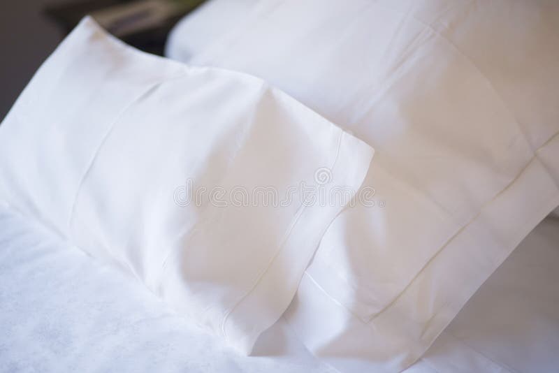 Luxury hotel bedroom bed clean ironed tidy cotton sheets and pillows ready for guests to sleep.