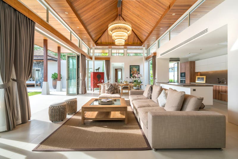 Luxury interior design in living room of pool villas. Airy and bright space with high raised ceiling and wooden dining table