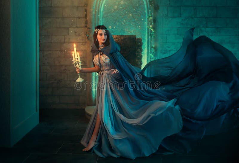 Luxury lady Queen medieval royal dress run escapes from Gothic night castle. Blue silk dress cloak train plume waving motion. Holds in hands old candlestick burning candles. Background old retro room. Luxury lady Queen medieval royal dress run escapes from Gothic night castle. Blue silk dress cloak train plume waving motion. Holds in hands old candlestick burning candles. Background old retro room