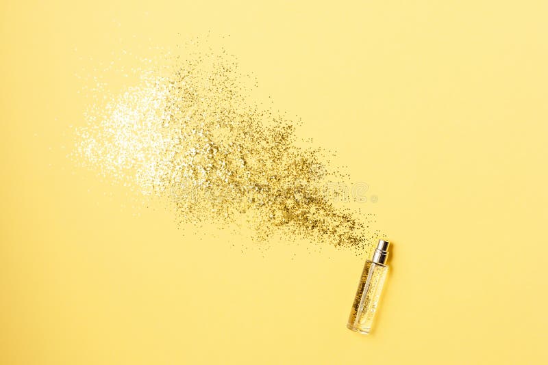 Luxury perfume concept. Stylish bottle of perfume with spray of sparkles on yellow background. Creative trendy flat lay