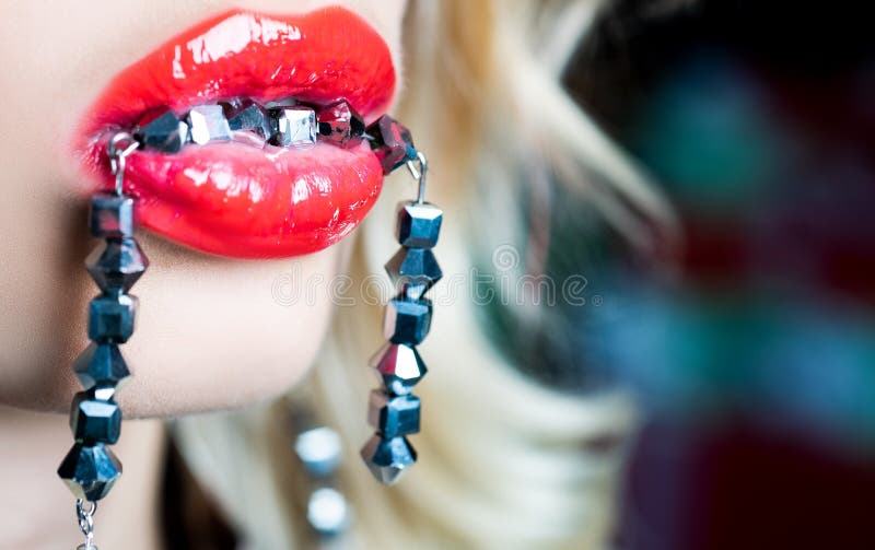 Luxury sexy lips. Bright female lips with red lipstick and with rhinestones. Jewelry in the mouth of a beautiful woman