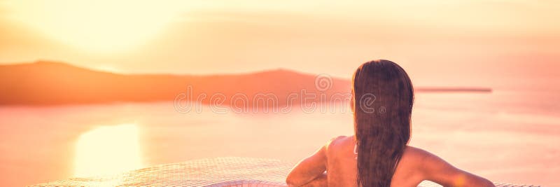 Luxury summer holiday travel destination in Europe woman relaxing in spa swimming pool watching sunset over Santorini