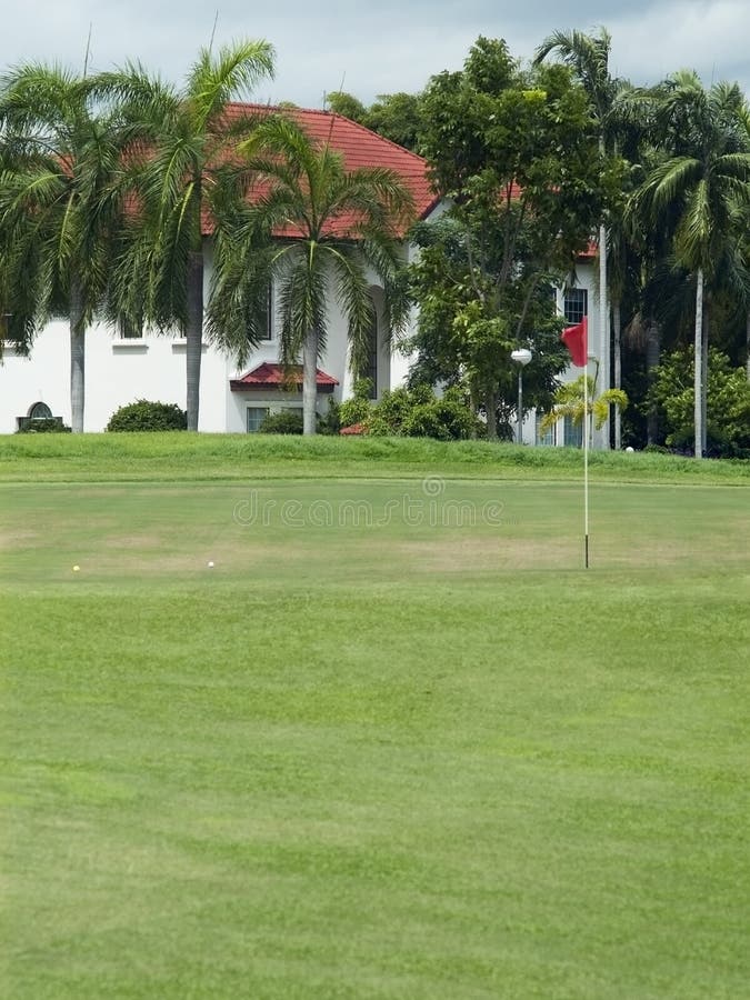 Luxury villa partly hidden behind palm trees near the green of a golf course in a tropical climate. Luxury villa partly hidden behind palm trees near the green of a golf course in a tropical climate.