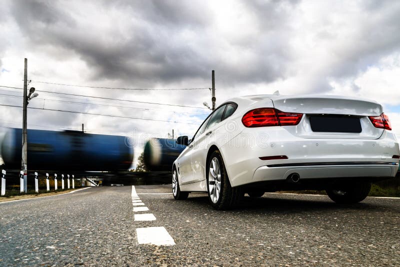 Luxury white car waiting at the railway crossing