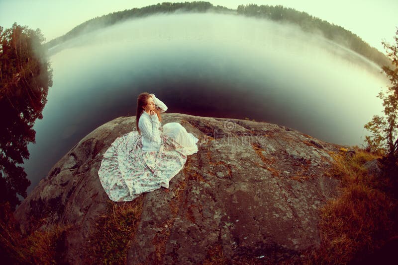 Luxury woman in a forest in a long vintage dress near the lake.