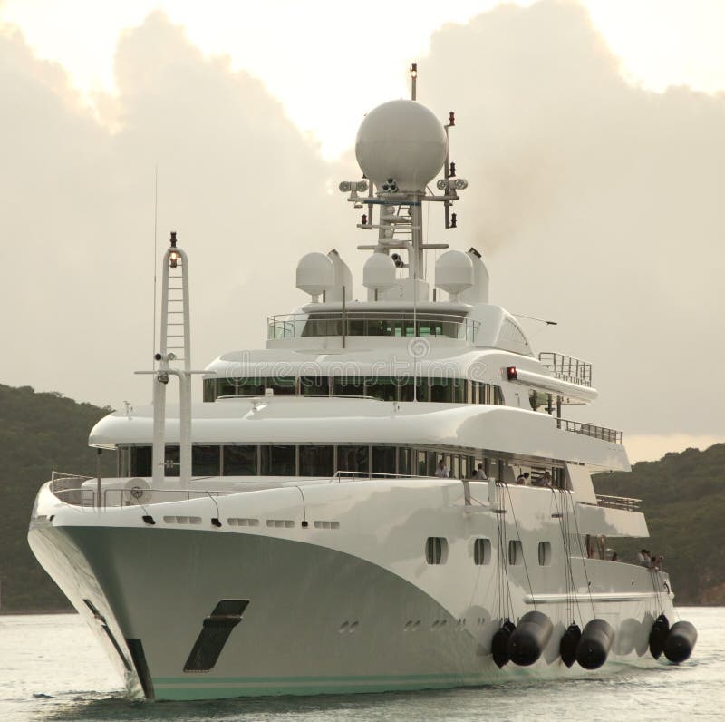 Tre piani di yacht di lusso di arrivare a un porto turistico, prepara con i suoi parafanghi.